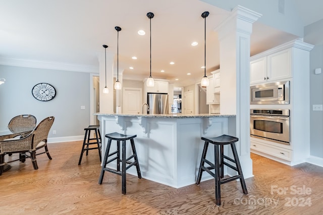 kitchen with hanging light fixtures, stainless steel appliances, light hardwood / wood-style floors, white cabinets, and ornamental molding