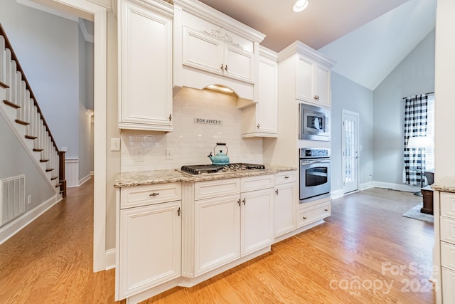 kitchen with white cabinets, stainless steel appliances, tasteful backsplash, and light hardwood / wood-style floors