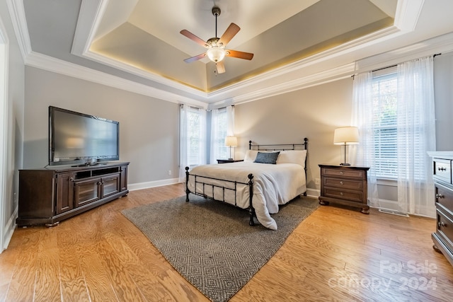 bedroom featuring a raised ceiling, multiple windows, and ceiling fan