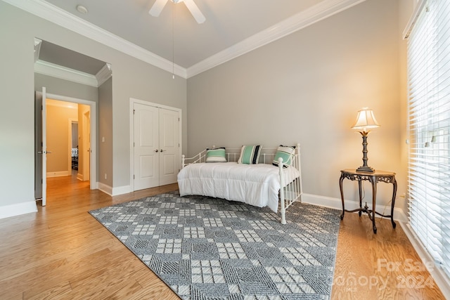 bedroom with hardwood / wood-style floors, a closet, ceiling fan, and crown molding