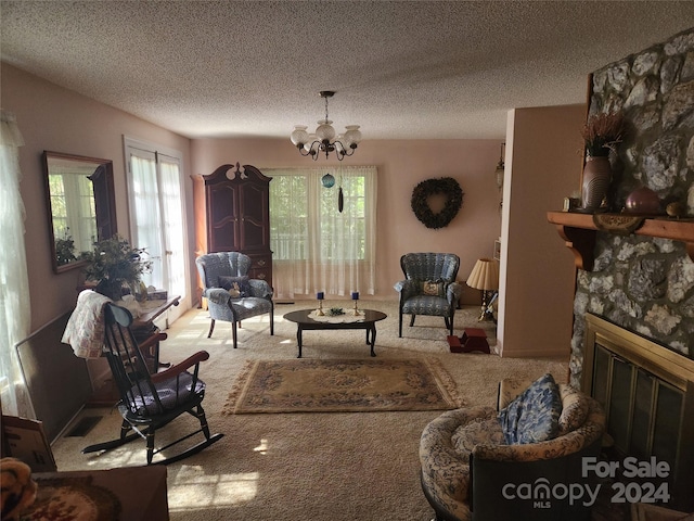 carpeted living area with a textured ceiling, a healthy amount of sunlight, a fireplace, and an inviting chandelier