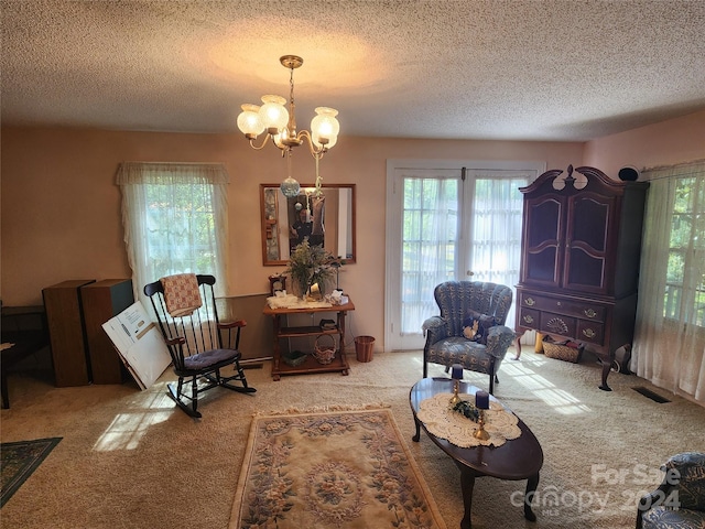 living area featuring plenty of natural light, a textured ceiling, a chandelier, and carpet flooring