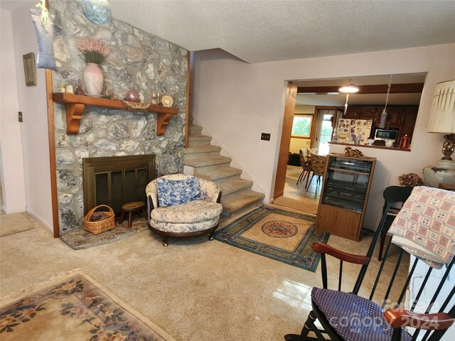 living area featuring stairs, a textured ceiling, and a fireplace