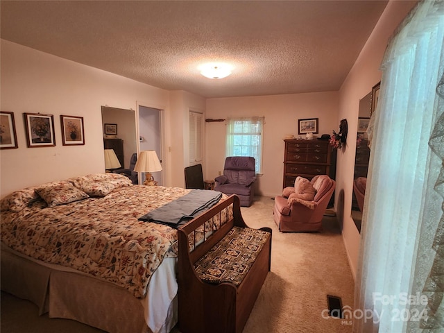 bedroom featuring light colored carpet and a textured ceiling