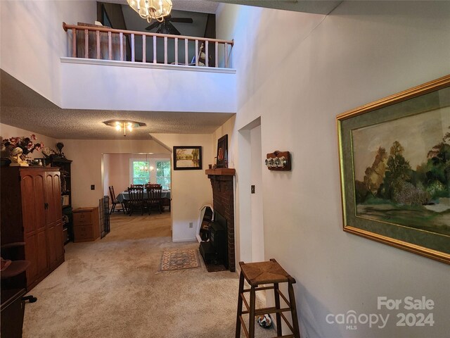 hallway featuring a textured ceiling, carpet, and a towering ceiling