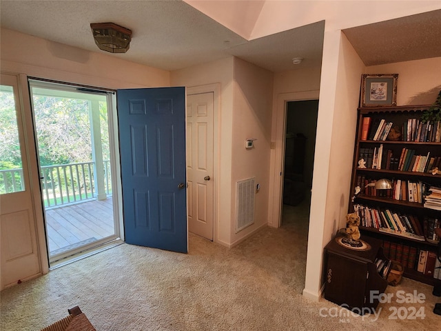 carpeted foyer featuring visible vents and a textured ceiling