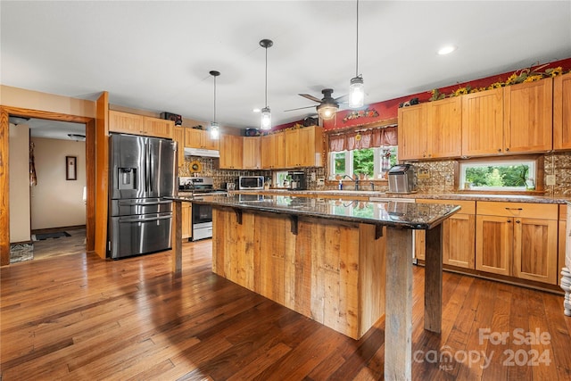 kitchen with a breakfast bar area, a kitchen island, stainless steel appliances, and ceiling fan