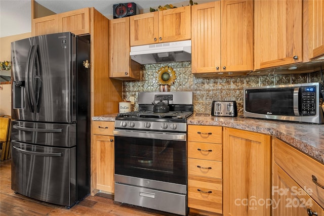 kitchen featuring appliances with stainless steel finishes, tasteful backsplash, and wood-type flooring