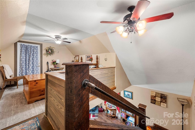 interior space with lofted ceiling, ceiling fan, wood-type flooring, and a textured ceiling