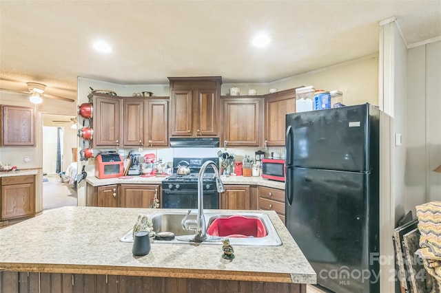 kitchen with sink, black appliances, ceiling fan, a center island with sink, and ornamental molding