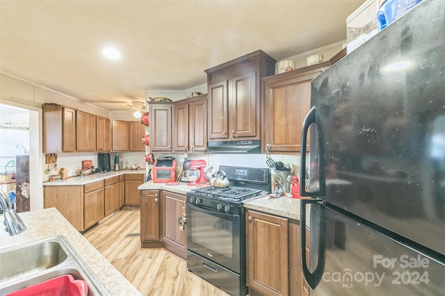 kitchen with a textured ceiling, black appliances, light hardwood / wood-style flooring, sink, and ceiling fan