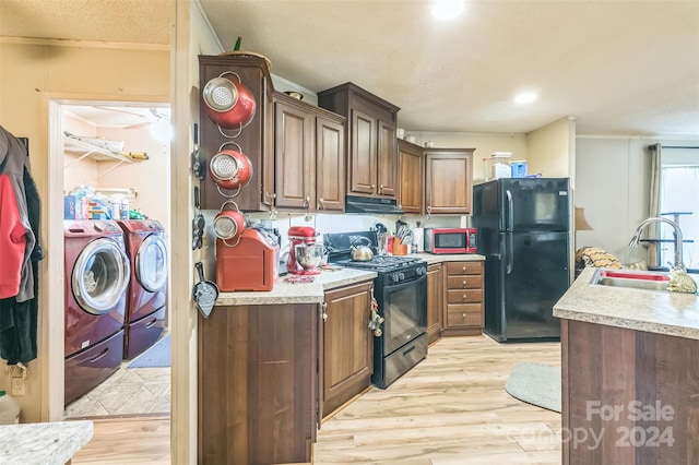 kitchen with light wood-type flooring, sink, black appliances, extractor fan, and separate washer and dryer