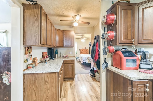 kitchen with light hardwood / wood-style flooring, ceiling fan, and a textured ceiling