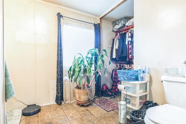 bathroom with a textured ceiling, toilet, and tile patterned flooring