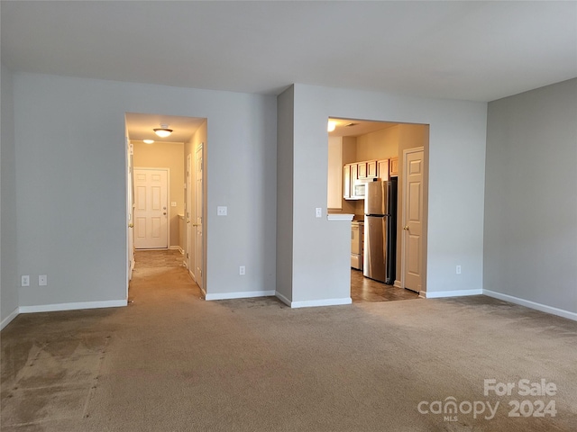 unfurnished bedroom featuring stainless steel fridge and light carpet