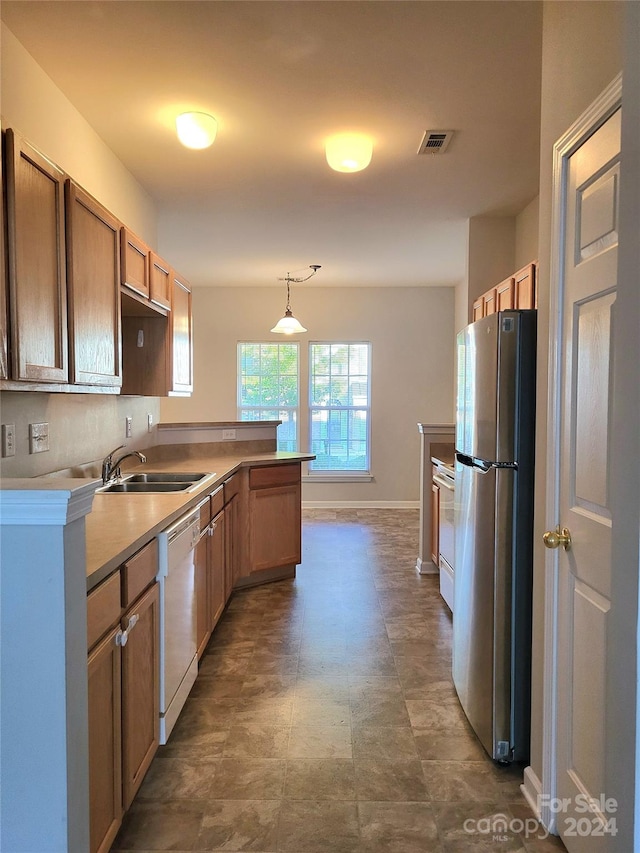 kitchen with hanging light fixtures, white dishwasher, sink, stainless steel fridge, and kitchen peninsula