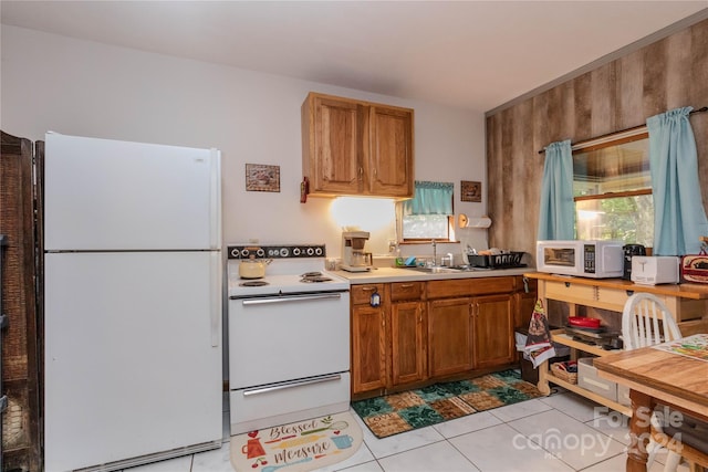 kitchen featuring sink, white appliances, and light tile patterned flooring