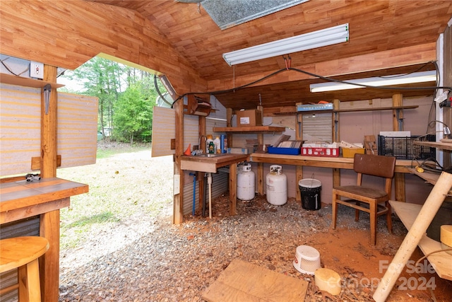 miscellaneous room featuring lofted ceiling, wood walls, and a workshop area