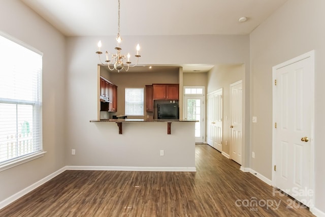 kitchen with black refrigerator, plenty of natural light, a breakfast bar area, and dark wood-type flooring