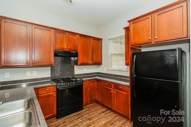 kitchen with light wood-type flooring, black appliances, and sink