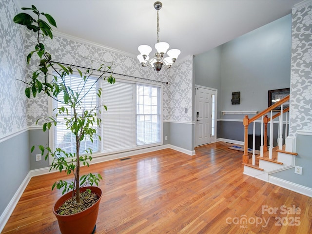 foyer entrance featuring an inviting chandelier, crown molding, and hardwood / wood-style floors