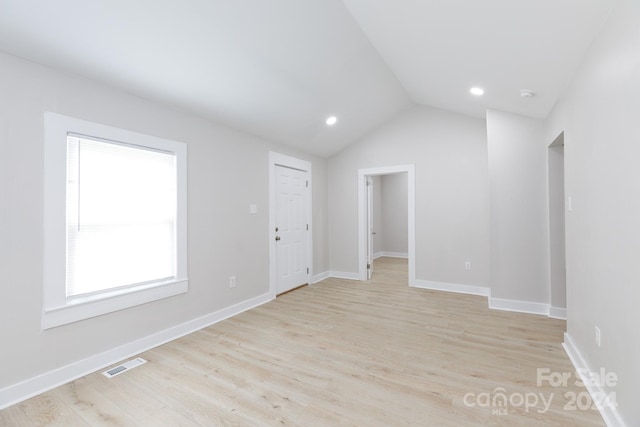 empty room featuring lofted ceiling and light hardwood / wood-style floors