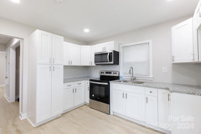 kitchen with light wood-type flooring, white cabinetry, stainless steel appliances, and sink