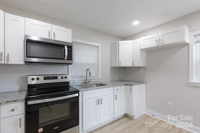 kitchen with appliances with stainless steel finishes, white cabinetry, and sink