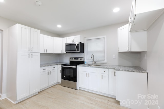 kitchen featuring light wood-type flooring, white cabinets, appliances with stainless steel finishes, and sink