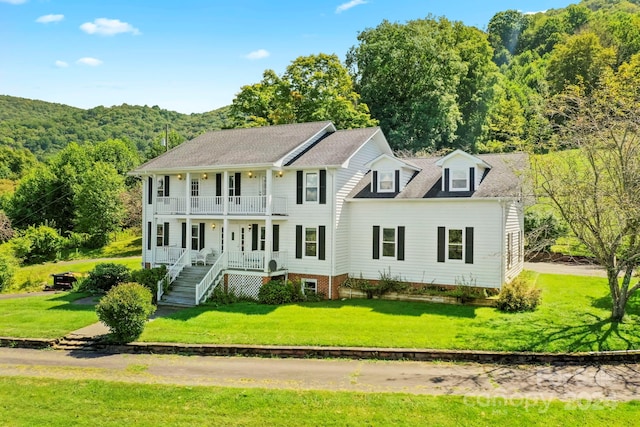 colonial house with a balcony and a front yard