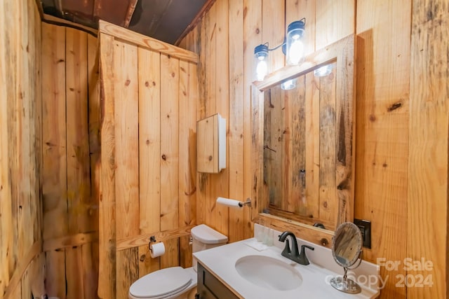 bathroom with vanity, toilet, and wood walls