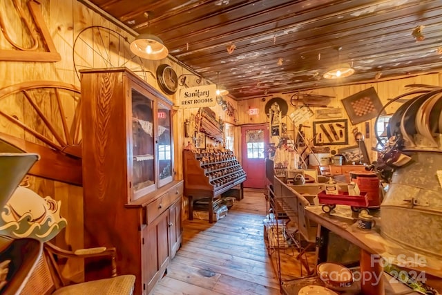 interior space featuring wood walls, decorative light fixtures, light wood-type flooring, and wooden ceiling