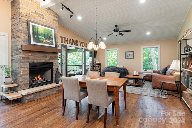 dining room featuring high vaulted ceiling, ceiling fan, a stone fireplace, hardwood / wood-style floors, and track lighting