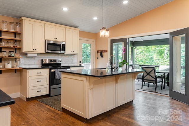 kitchen with stainless steel appliances, dark hardwood / wood-style floors, a center island with sink, and vaulted ceiling