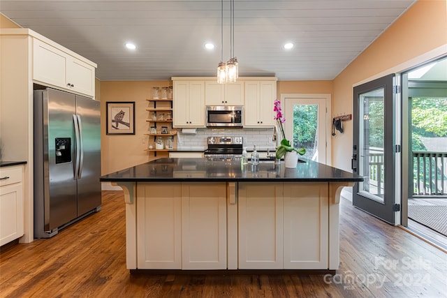 kitchen with dark wood-type flooring, appliances with stainless steel finishes, a breakfast bar, and a kitchen island with sink