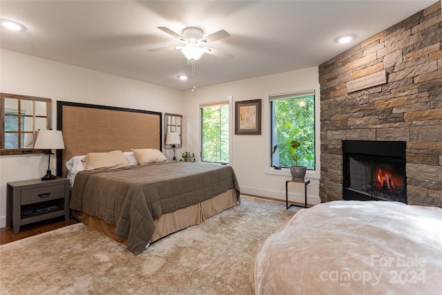 bedroom with a fireplace, ceiling fan, and light hardwood / wood-style flooring