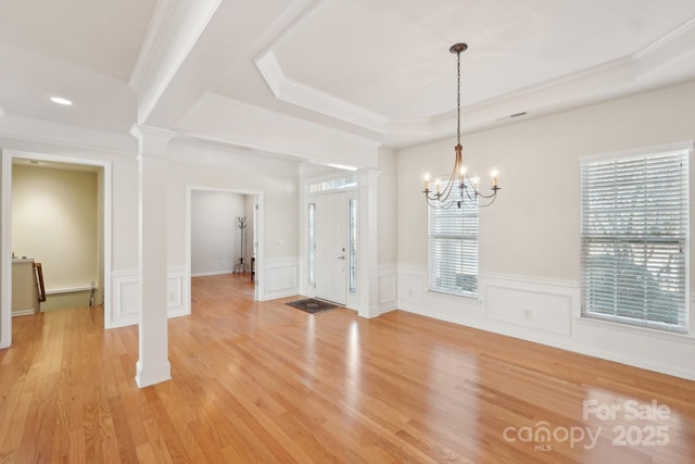 interior space featuring a notable chandelier, a tray ceiling, wood-type flooring, and plenty of natural light