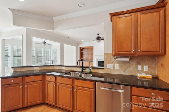 kitchen featuring sink, dark stone countertops, crown molding, and kitchen peninsula