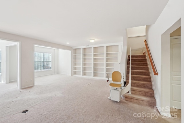 unfurnished living room featuring carpet floors and built in shelves