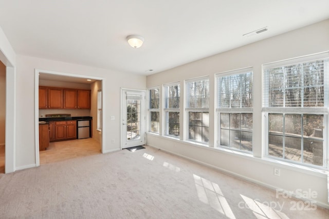 unfurnished living room with light carpet and plenty of natural light