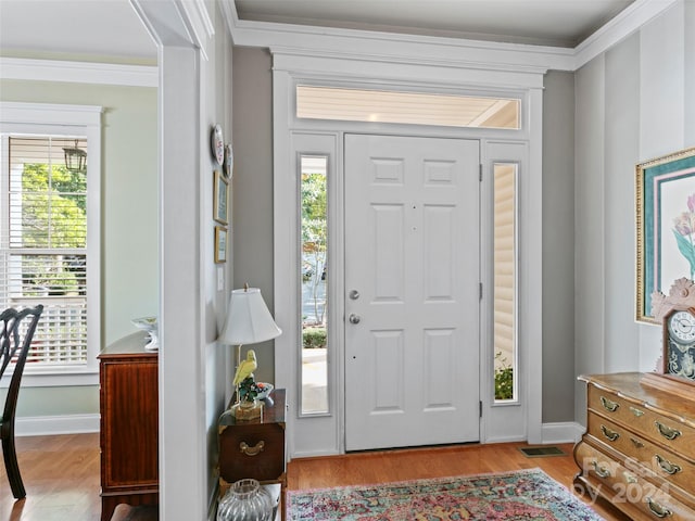 entrance foyer featuring crown molding and light hardwood / wood-style floors