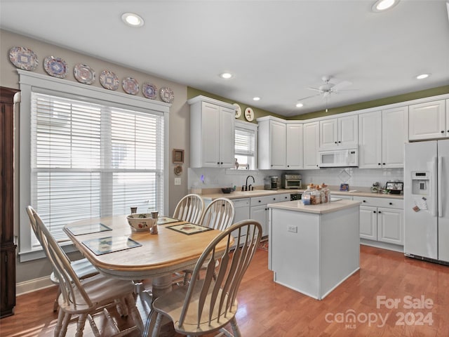 kitchen featuring white cabinets, sink, white appliances, a center island, and light hardwood / wood-style floors