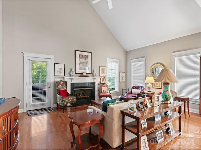 living room featuring high vaulted ceiling, a wealth of natural light, a tile fireplace, and hardwood / wood-style flooring