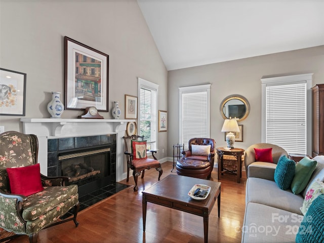 living room featuring high vaulted ceiling, a tile fireplace, and hardwood / wood-style floors