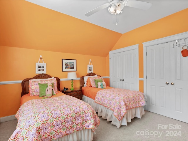 bedroom with two closets, lofted ceiling, ceiling fan, and carpet flooring