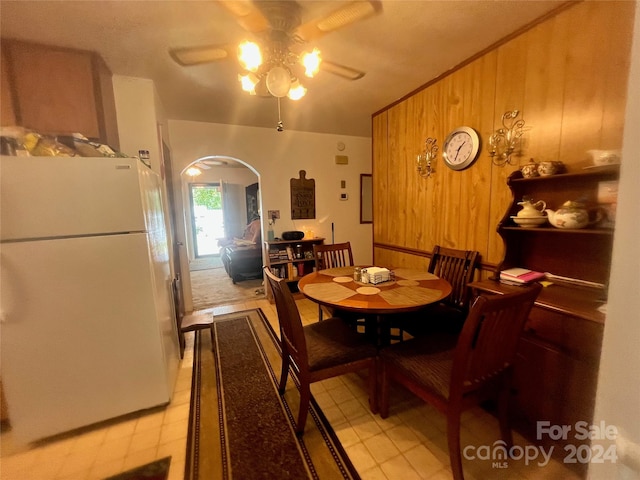 dining area with ceiling fan and wooden walls