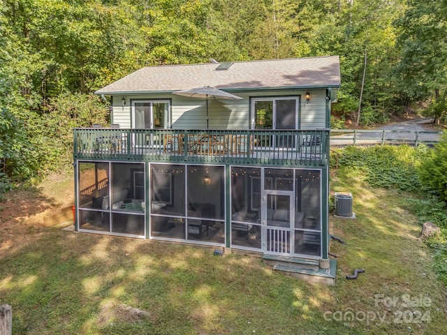 rear view of property featuring a yard, a wooden deck, a sunroom, and central AC unit