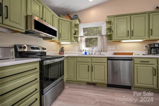 kitchen featuring vaulted ceiling, appliances with stainless steel finishes, light hardwood / wood-style floors, sink, and green cabinetry