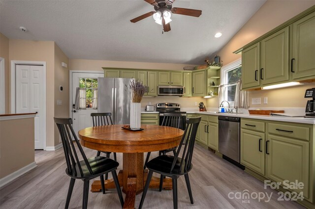 kitchen with lofted ceiling, stainless steel appliances, green cabinetry, and ceiling fan