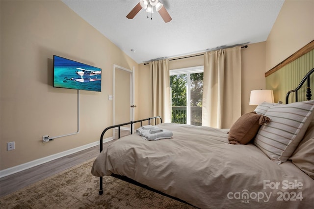 bedroom with lofted ceiling, hardwood / wood-style floors, ceiling fan, and a textured ceiling